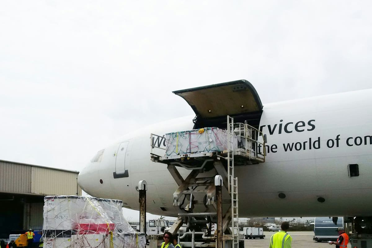 Ground crew loading palletised cargo through the nose door of a freighter aircraft