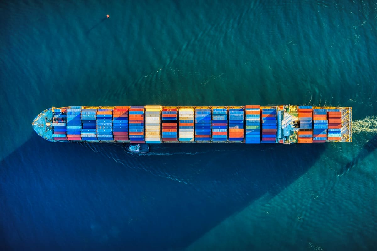 Overhead view of a container ship under way on open water, deck stacked with containers