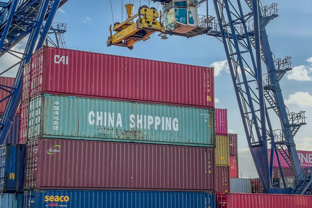 A spreader lowering a shipping container onto a stack at a container terminal